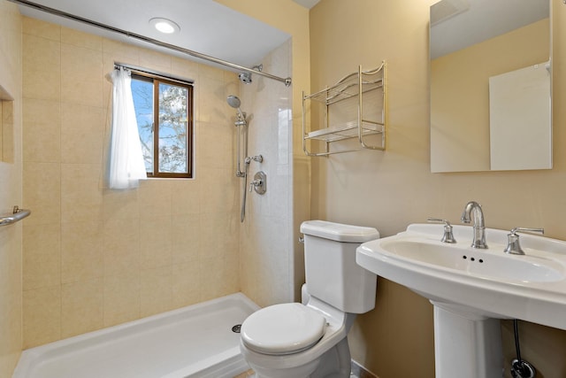 bathroom featuring toilet, sink, and a tile shower