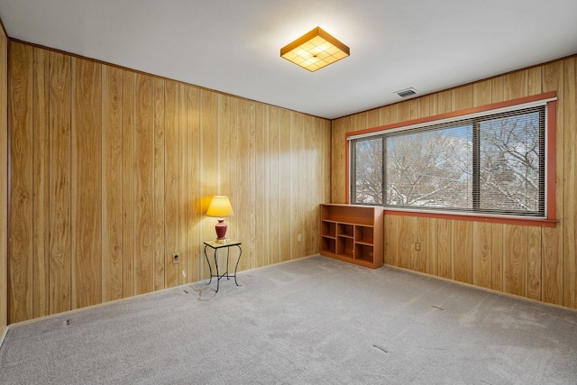 carpeted spare room with wood walls