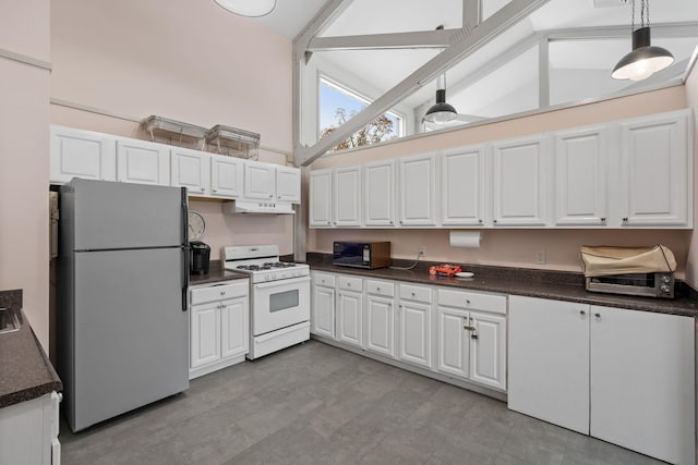 kitchen featuring high vaulted ceiling, white gas range, white cabinets, hanging light fixtures, and fridge