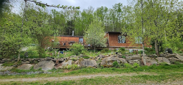 rear view of property with a deck and a view of trees