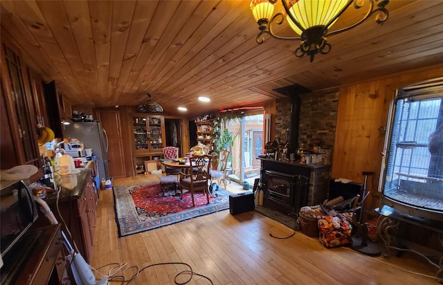 dining room featuring wood ceiling, a wood stove, and hardwood / wood-style flooring