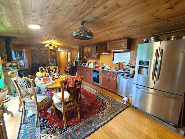 dining room with wood walls, wood ceiling, and light wood-style flooring