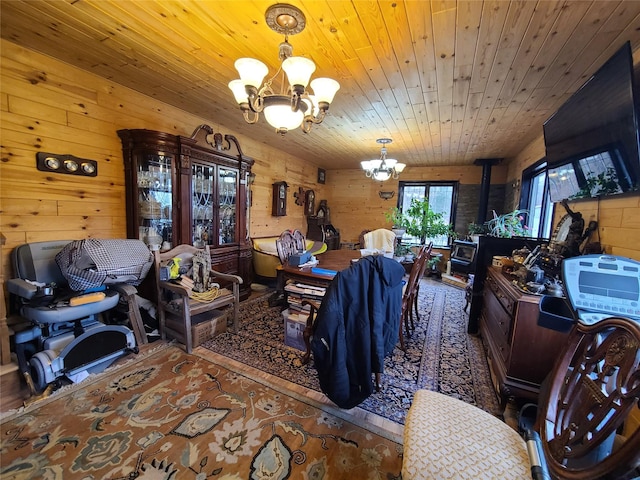 dining room featuring a wood stove, an inviting chandelier, wooden walls, and wooden ceiling