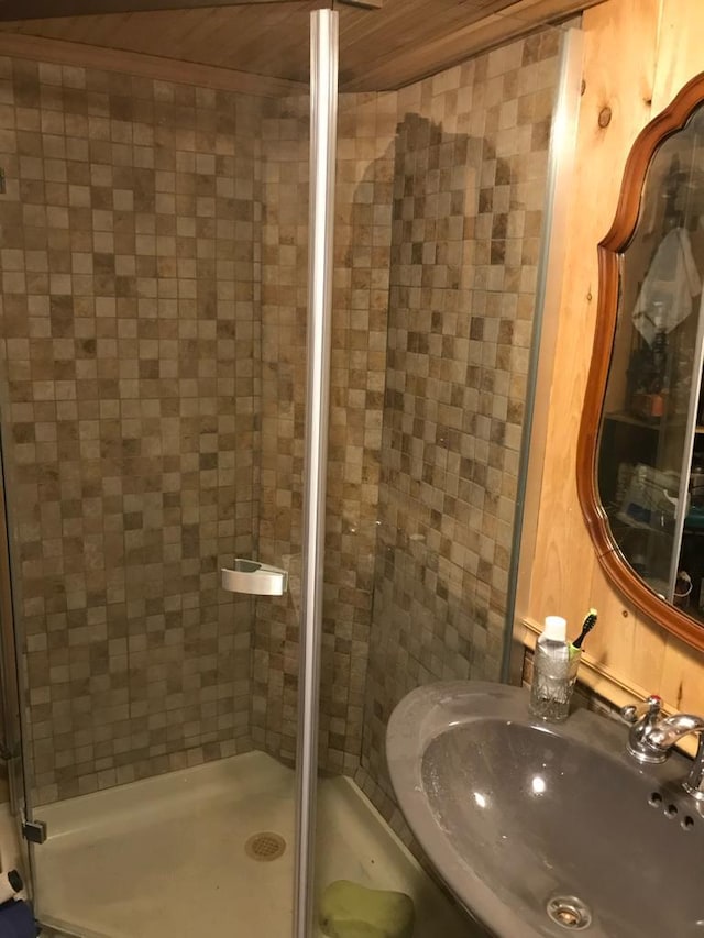 bathroom featuring wood ceiling, a sink, and a shower stall