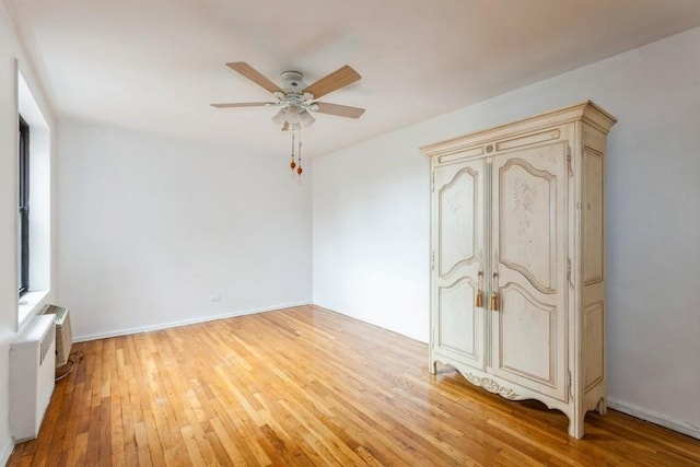 unfurnished bedroom featuring radiator heating unit, ceiling fan, and light hardwood / wood-style flooring