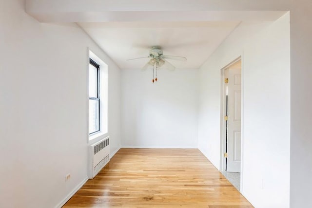 unfurnished room featuring ceiling fan, radiator, and light wood-type flooring