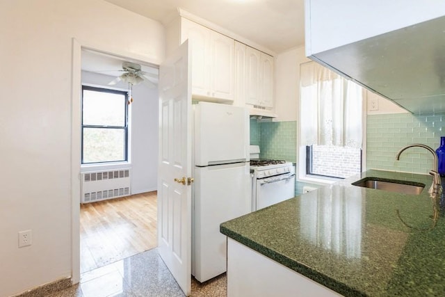 kitchen featuring sink, tasteful backsplash, radiator, white appliances, and white cabinets