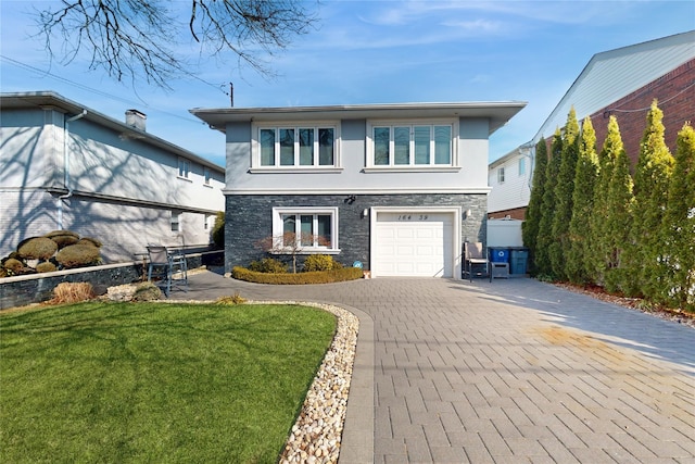 view of front facade with stone siding, a front lawn, decorative driveway, and stucco siding