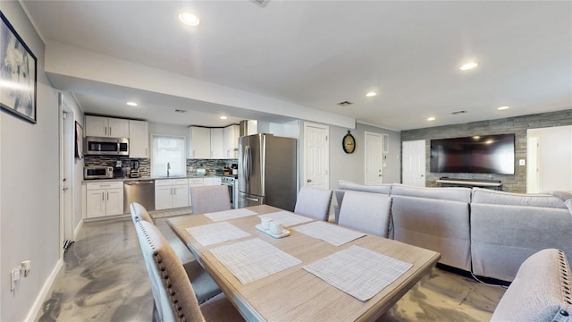 dining room featuring baseboards, recessed lighting, and finished concrete floors