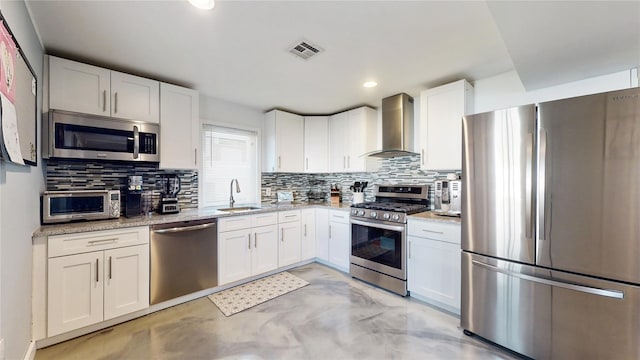 kitchen with a sink, visible vents, appliances with stainless steel finishes, wall chimney range hood, and decorative backsplash