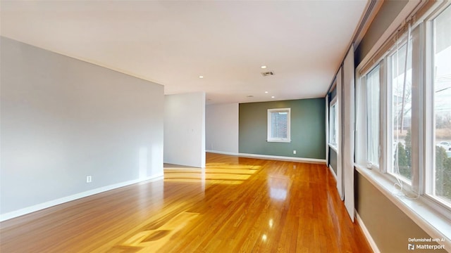 unfurnished room featuring a healthy amount of sunlight, light wood-style floors, and baseboards