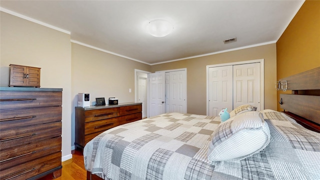 bedroom with visible vents, baseboards, multiple closets, ornamental molding, and light wood finished floors