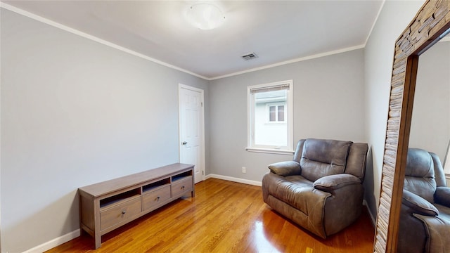 sitting room featuring baseboards, crown molding, visible vents, and light wood-style floors