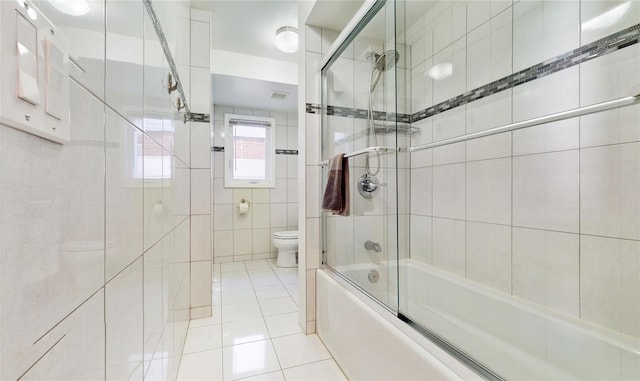 bathroom featuring bath / shower combo with glass door, tile patterned flooring, and toilet