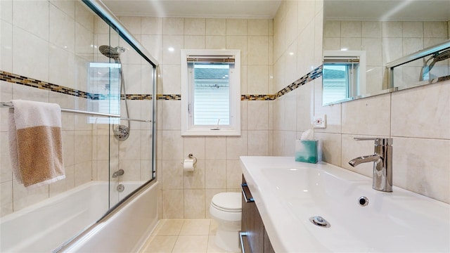 full bathroom with shower / bath combination with glass door, tile walls, toilet, vanity, and tile patterned flooring