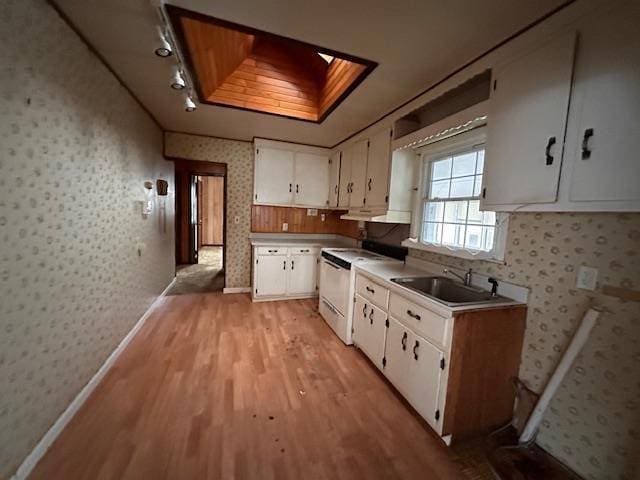 kitchen featuring white electric stove, light countertops, white cabinets, a sink, and wallpapered walls