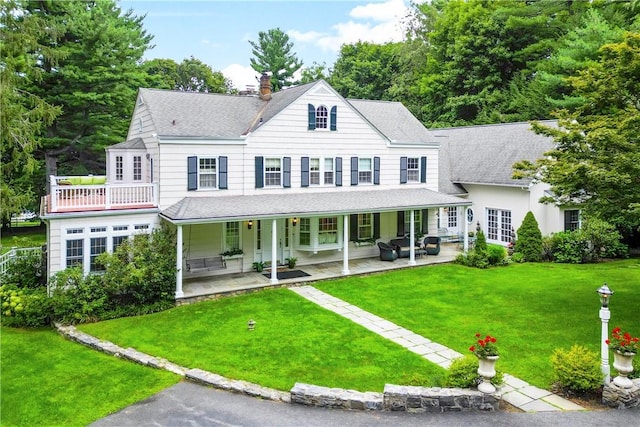 view of front facade featuring a shingled roof, a chimney, and a front lawn