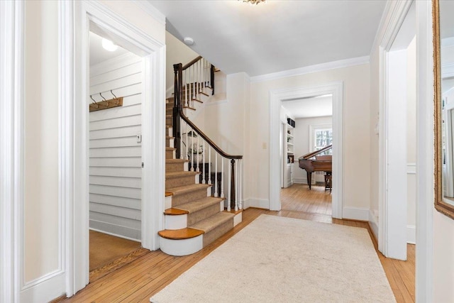 foyer with baseboards, stairs, ornamental molding, and wood finished floors