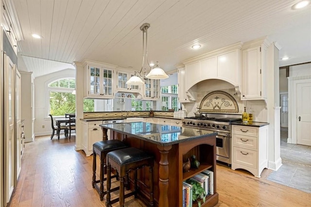 kitchen with range with two ovens, lofted ceiling, glass insert cabinets, a breakfast bar, and a center island