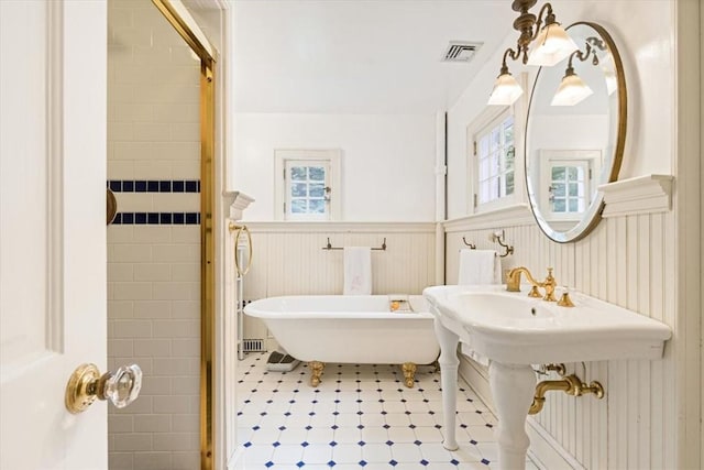 bathroom with a wainscoted wall, a freestanding bath, and visible vents