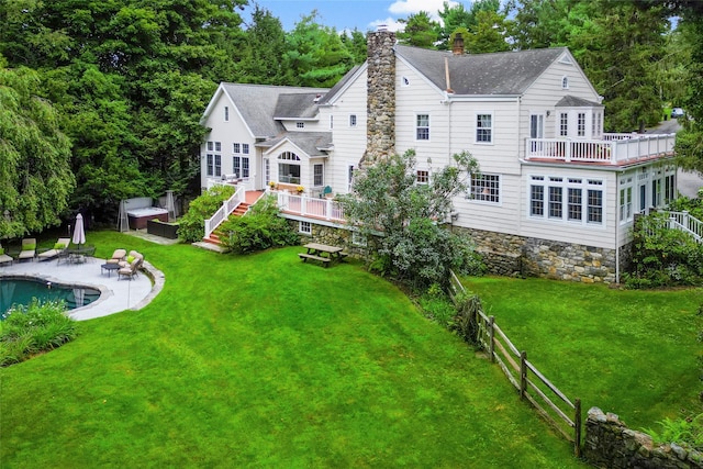 rear view of house with a patio, fence, a yard, an outdoor pool, and a chimney