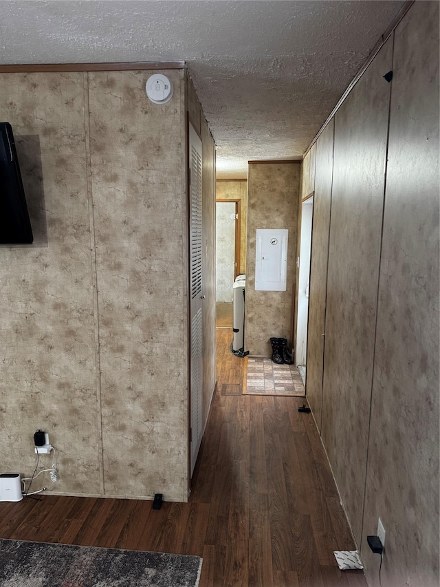 hall with a textured ceiling, electric panel, washer / clothes dryer, and wood finished floors