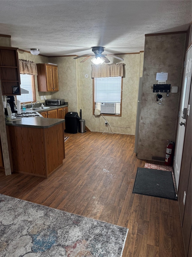 kitchen with dark countertops, brown cabinets, dark wood-type flooring, a textured ceiling, and cooling unit