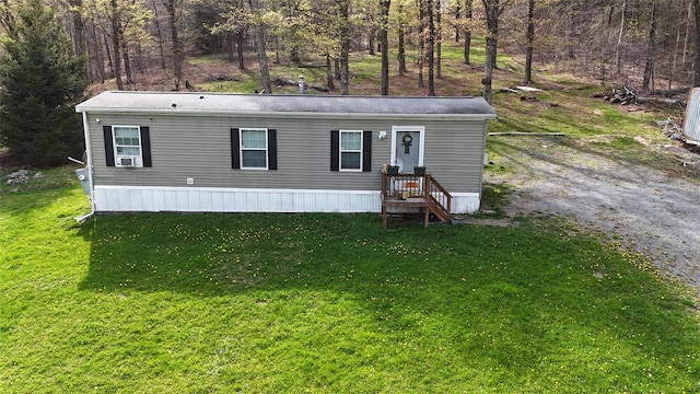 manufactured / mobile home featuring a front lawn and a forest view