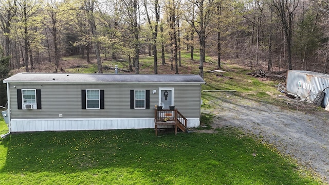 manufactured / mobile home with cooling unit, an outbuilding, and a front lawn
