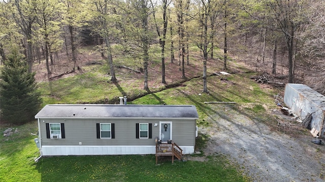 manufactured / mobile home featuring a wooded view and a front yard