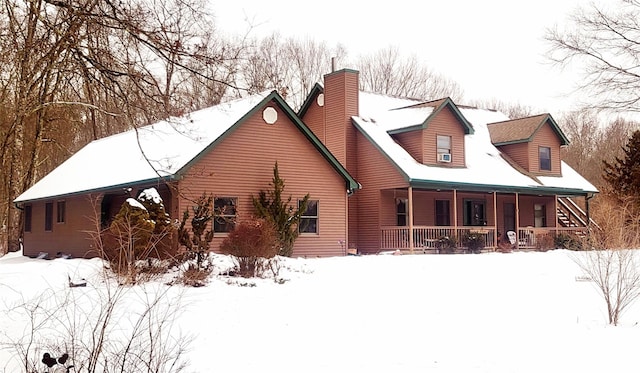 snow covered back of property featuring a porch