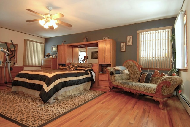 bedroom with a baseboard radiator, light hardwood / wood-style floors, and ceiling fan