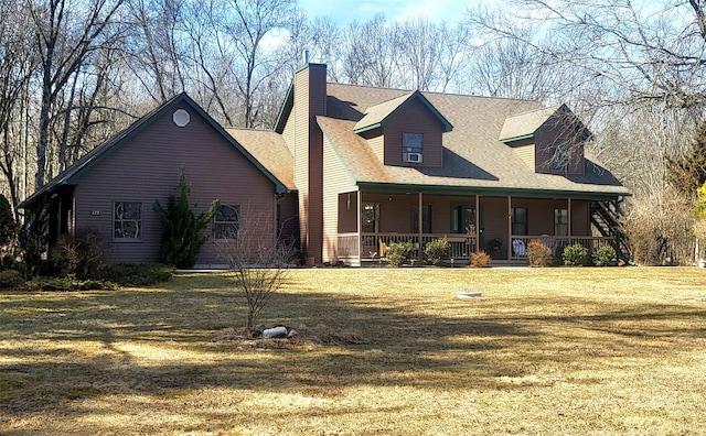 rear view of house with a yard, roof with shingles, a porch, and a chimney