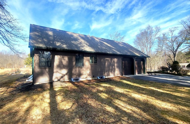 view of home's exterior featuring an attached garage, driveway, and a shingled roof