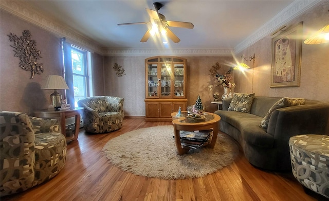 living room with a ceiling fan, wood finished floors, wallpapered walls, and ornamental molding
