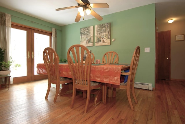 dining room featuring a baseboard heating unit, light wood-style flooring, french doors, and a ceiling fan