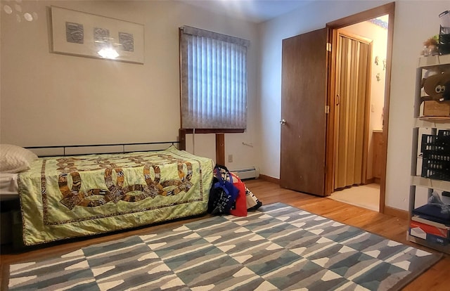 bedroom featuring a baseboard radiator, baseboards, and wood finished floors