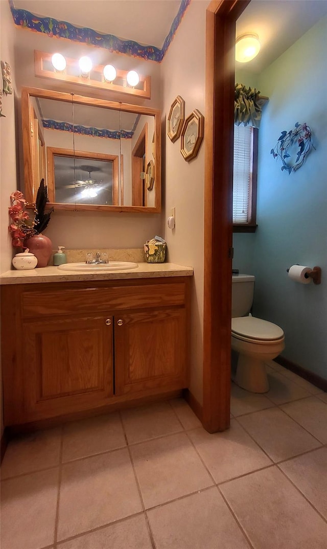 half bathroom with tile patterned floors, baseboards, toilet, and vanity