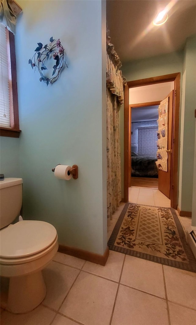 bathroom with curtained shower, baseboards, toilet, and tile patterned flooring