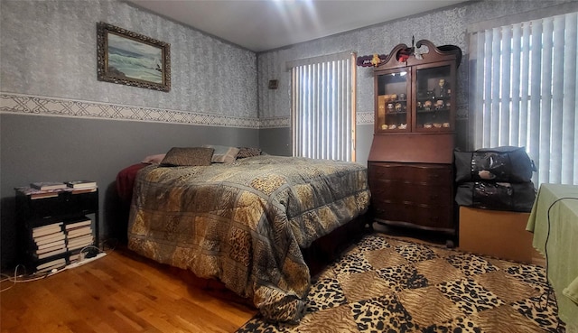 bedroom featuring wallpapered walls and wood finished floors