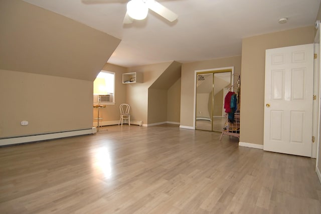 additional living space featuring an AC wall unit, wood finished floors, a baseboard radiator, baseboards, and ceiling fan