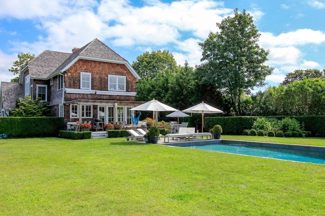 rear view of house featuring a fenced in pool, a patio, and a lawn