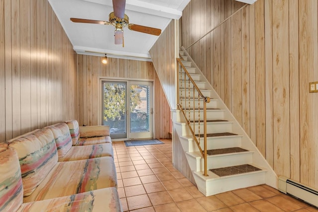 unfurnished living room featuring a baseboard heating unit, wooden walls, ceiling fan, and light tile patterned floors