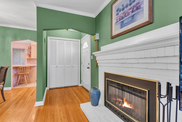 interior space featuring ornamental molding, a brick fireplace, decorative backsplash, and wood-type flooring