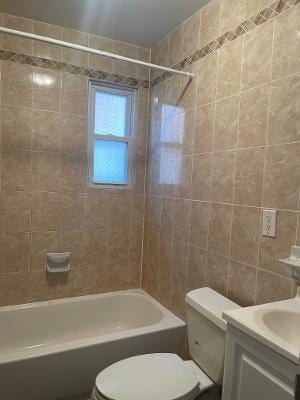 full bath with toilet, bathing tub / shower combination, tile walls, and vanity