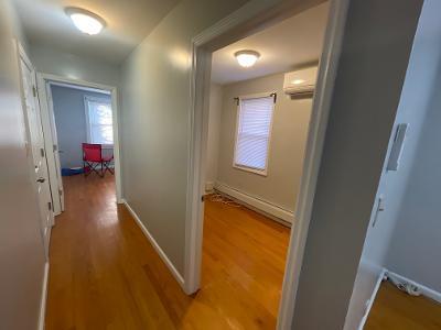hallway featuring baseboards, wood finished floors, and a wall mounted air conditioner