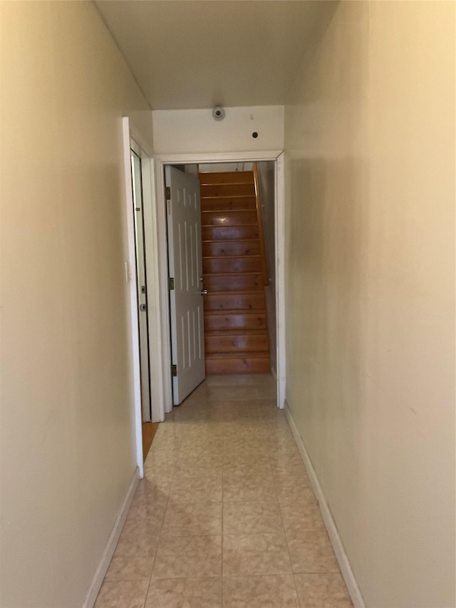 corridor with light tile patterned flooring and baseboards
