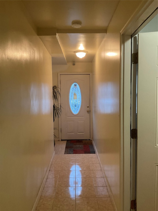 doorway with light tile patterned floors and baseboards