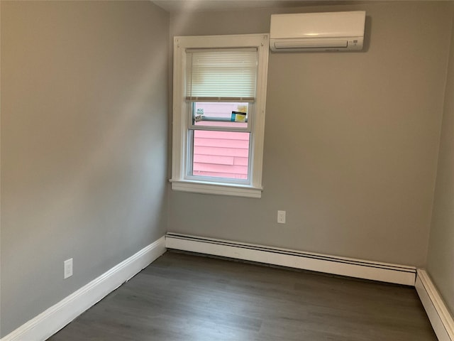 spare room featuring a baseboard heating unit, a wall unit AC, dark wood finished floors, and baseboards