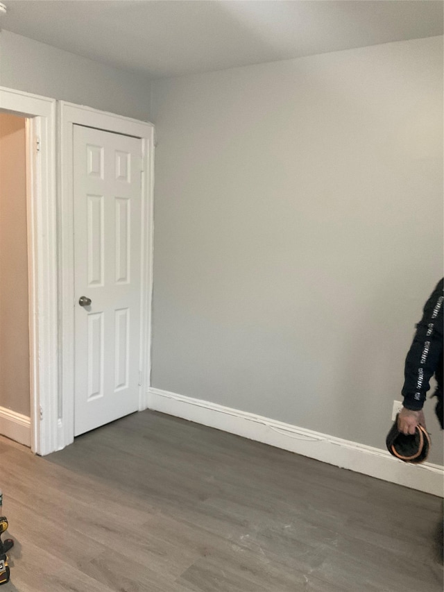 spare room with baseboards and wood finished floors